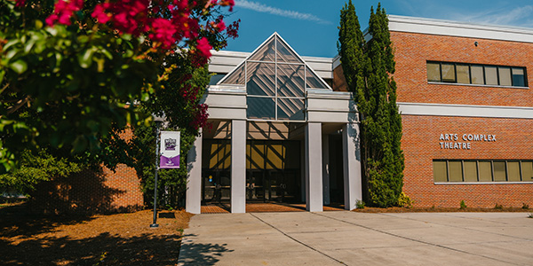 Image of the front of the School of Arts and Letters on MGA's Macon Campus, framed by red Crepe Myrtles.